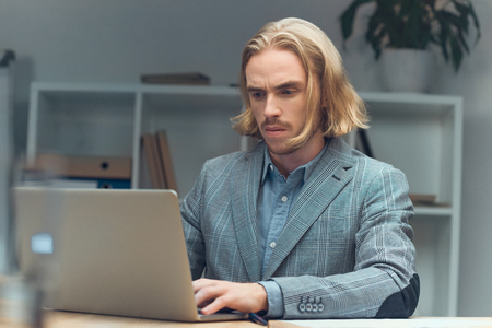 Caucasian man using laptop on table at office spaceの写真素材