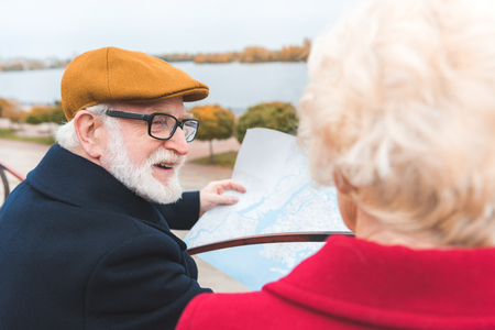 senior tourist couple looking at map while walking in cityの写真素材