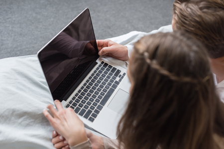 Cropped image of couple lying and looking at the laptop の写真素材