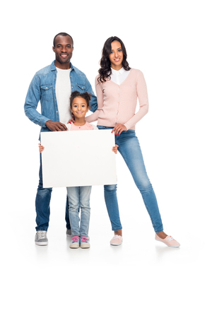 happy african american family holding blank card and smiling at camera isolated on whiteの写真素材