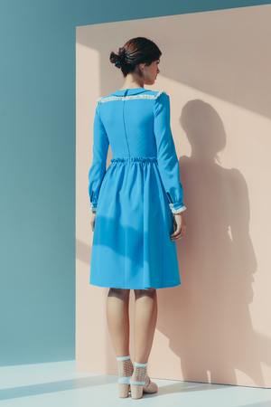 Back view of beautiful woman standing in fashionable turquoise dress with long sleevesの写真素材