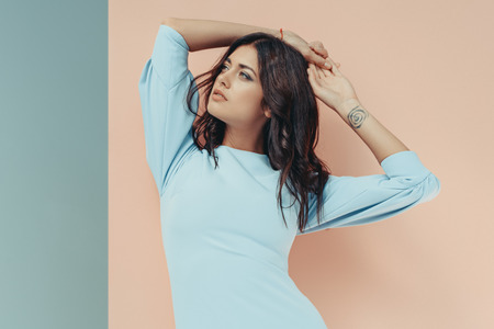 Beautiful woman standing in fashionable turquoise dress looking away 