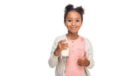 cute african american child drinking milk and showing thumb up isolated on whiteの写真素材