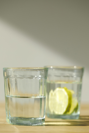 close up view of glass with water and glass with lemonadeの写真素材