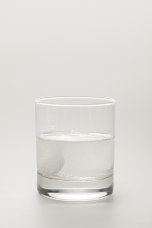 effervescent pill in glass of water isolated on whiteの写真素材