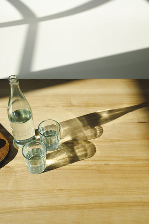 overhead view of transparent bottle and glasses with mineral waterの写真素材
