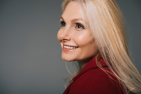 close-up portrait of smiling mature woman isolated on grey