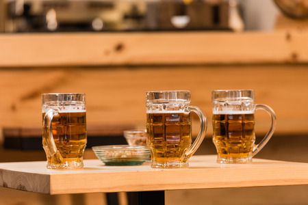close-up view of cool beer in glasses and snacks on table in bar