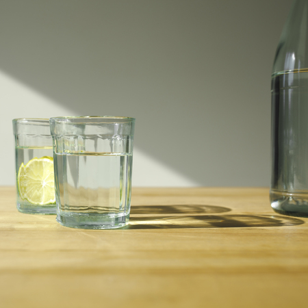glasses with detox water with limes on wooden tableの写真素材