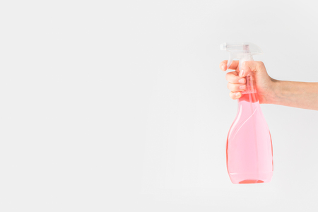 cropped view of hand holding pink spray bottle, isolated on whiteの写真素材