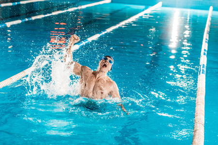 handsome winning muscular swimmer in competition swimming poolの写真素材
