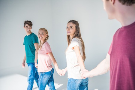 happy young people holding hands on greyの写真素材