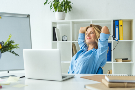 beautiful happy businesswoman with laptop at workplace in modern officeの写真素材
