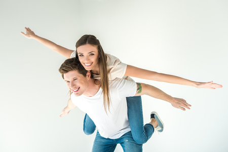 beautiful happy young couple piggybacking isolated on whiteの写真素材