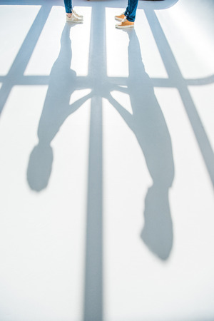 partial view of young standing together and shadows on greyの写真素材