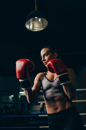 athletic young woman in boxing gloves training in sport clubの写真素材