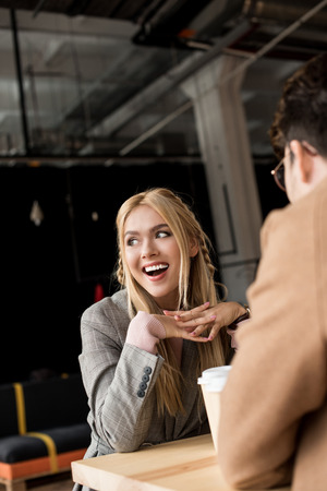 Girl laughing while sitting at cafe with young manの写真素材