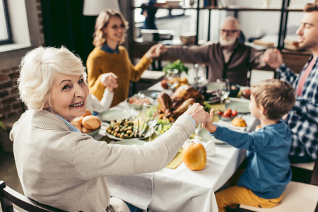 family holding hands and praying on thanksgiving before holiday dinnerの写真素材