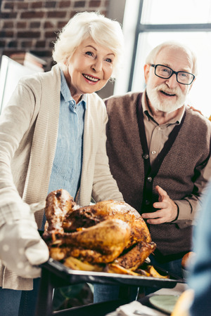 happy senior couple with thanksgiving turkey on trayの写真素材