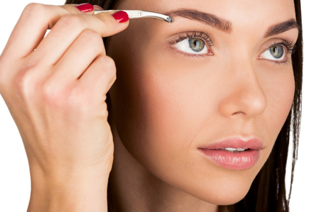 young attractive woman doing eyebrow correction isolated on white