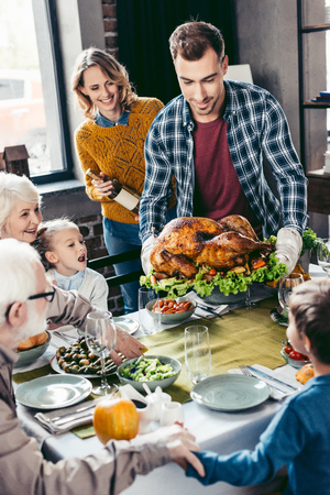 handsome man with delicious turkey for holiday dinner with familyの写真素材