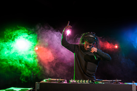 professional african american club DJ in headphones with microphone in nightclub 