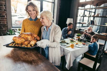 senior mother and daughter with thanksgiving turkey for family dinner at homeの写真素材