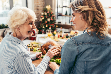 happy senior mother and daughter celebrating christmas togetherの写真素材