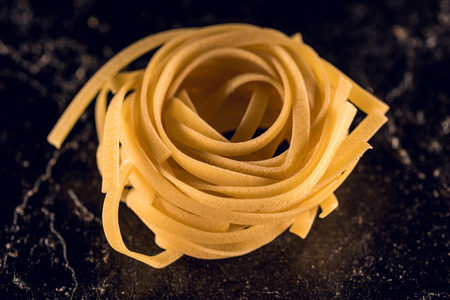raw pasta nest on black concrete tableの写真素材