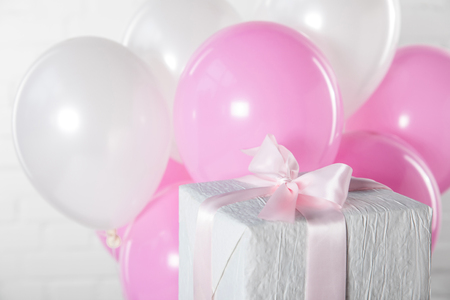 Gift box and balloons on white brick wall backgroundの写真素材