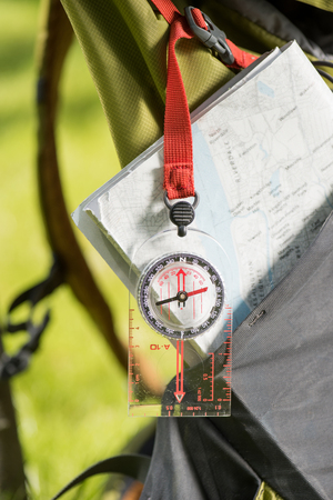 close-up view of compass hanging on backpack and mapの写真素材