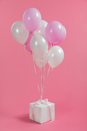 Bunch of balloons tied on gift box on pink backgroundの写真素材