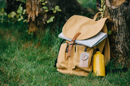 close-up view of backpack with compass and map on green grassの写真素材