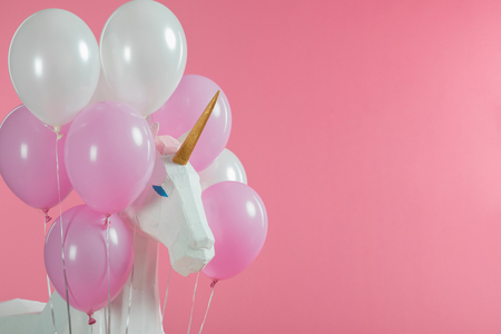 Toy unicorn among pink and white balloons isolated on pinkの写真素材