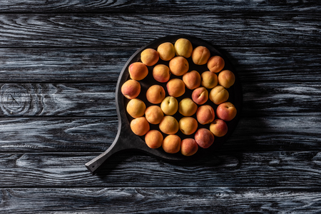 top view of pile of ripe apricots in tray on wooden tableの写真素材