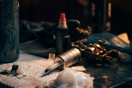 close up view of tattoo machine, ink and other equipment for tattooing process