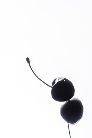 close up view of cherry on surface with reflection on whiteの写真素材
