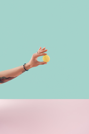 cropped view of tattooed hand with yellow macaronの写真素材