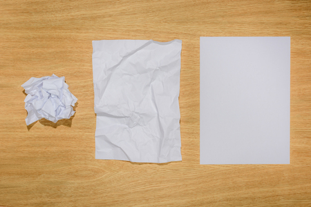 top view of crumpled papers and blank white paper on wooden tableの写真素材