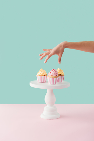 cropped view of woman taking cupcakes from cake standの写真素材