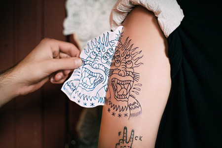 cropped shot of tattoo artist transferring tattoo sketch on shoulder in tattoo salonの写真素材