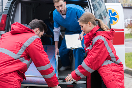 young paramedics moving ambulance stretcher from carの写真素材
