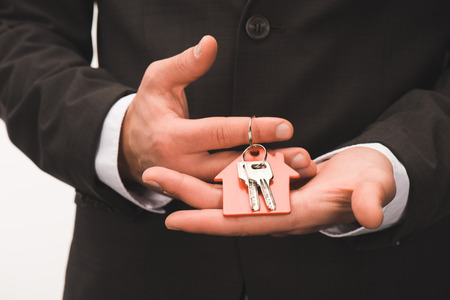 cropped image of man holding key from house isolated on white