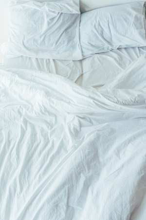top view of bed with white bedding, pillows and blanket