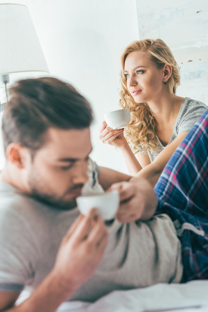 selective focus of young couple drinking coffee in bedの写真素材
