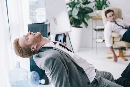 exhausted businessman sleeping on chair at messy officeの写真素材