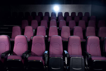 red seats in empty dark movie theater with back lightの写真素材