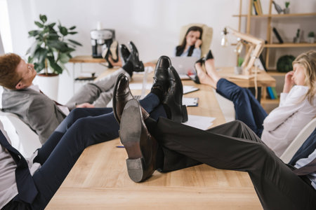 businesspeople sitting in conference hall with feet on tableの写真素材