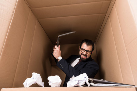 aggressive businessman with paperwork and cardboard laptop in boxの写真素材