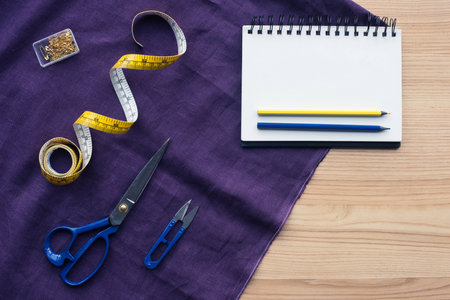 top view of table with sewing tools over purple fabric
